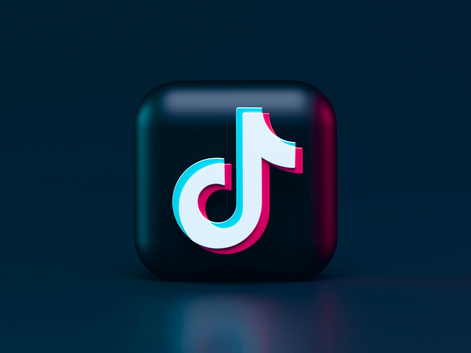 A three-dimensional TikTok logo with cyan and magenta chromatic aberration on a dark background